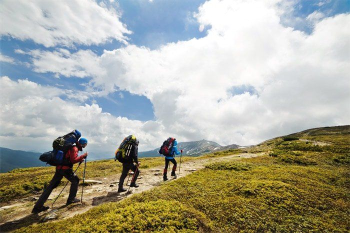 Drei Wanderer in Berglandschaft bei leicht bewölktem Wetter